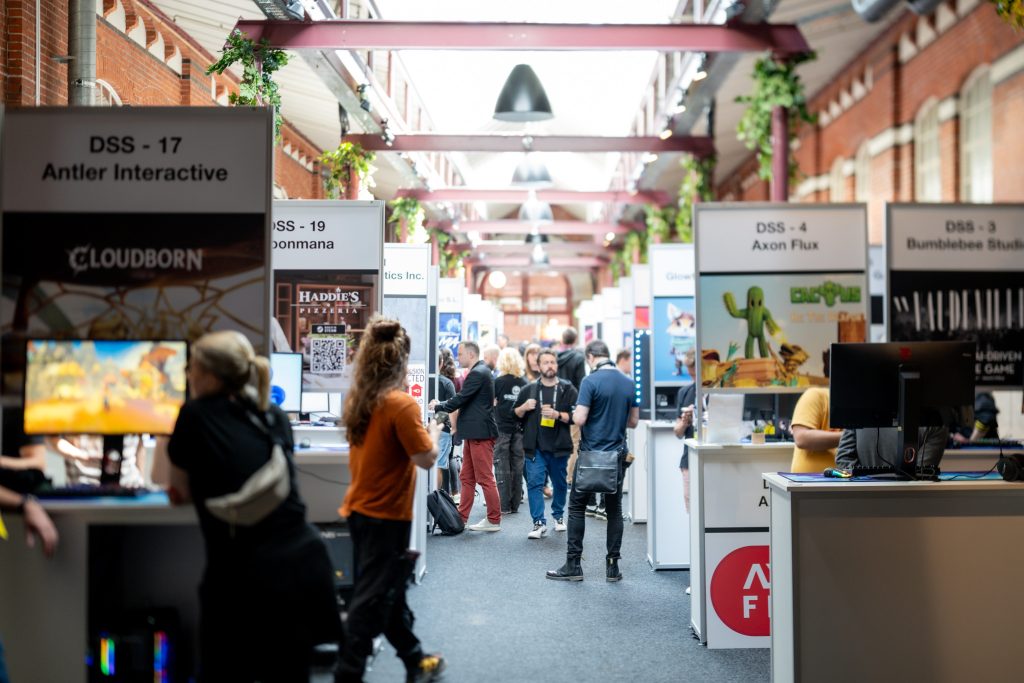 Mastering Game Trade Show PR: An image of a busy indoor trade show aisle with various company booths, demonstrating a typical game trade show environment. 